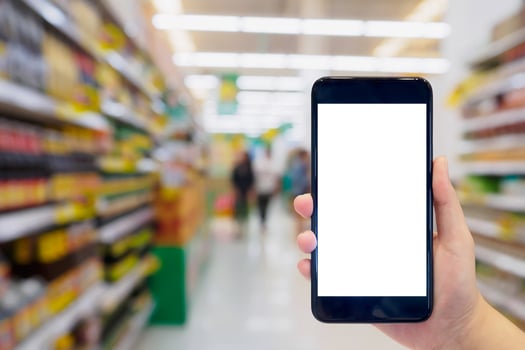 Woman hold mobile phone while shopping in supermarket photo