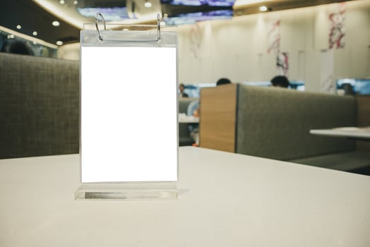 Mockup empty white label menu frame on table with cafe restaurant interior background photo