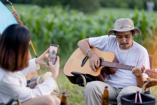 Happy Asian Couple Play guitar and sing enjoy camping and drinking beer. photo