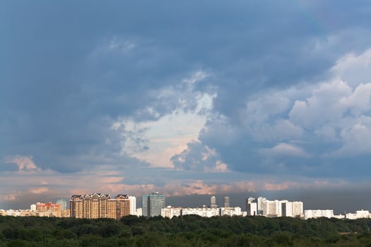 dark rainy clouds in sunset sky over city photo