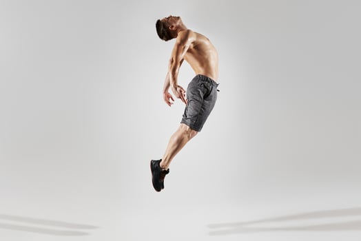 Confident muscular man with perfect body jumping against white background photo