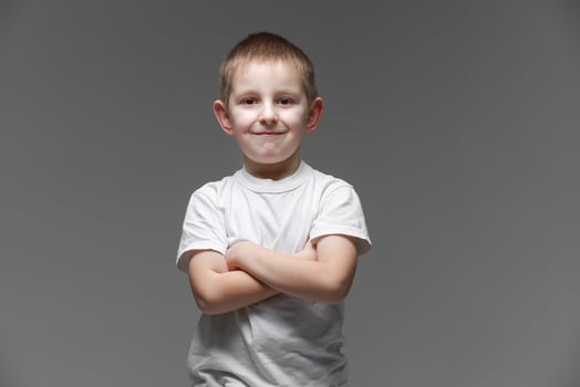 Portrait of happy little boy in white t-shirt smiling on gray background looking at camera in studio setting. Portrait of fashionable male child. photo