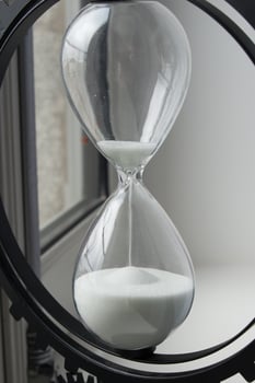 Close up of an hourglass with sand flowing from the upper part photo