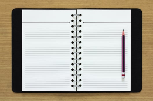 blank spiral notebook and pencil on wood background photo