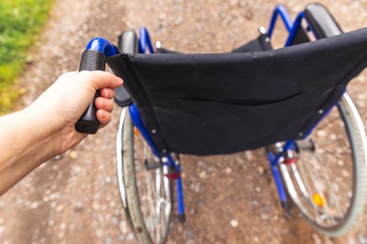 Hand holding empty wheelchair in hospital park waiting for patient services. Wheel chair for person with disability parked outdoor. Accessible for person with disability. Health care medical concept. photo