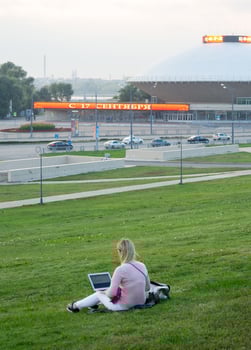 Girl working in a laptop on the lawn in the city photo
