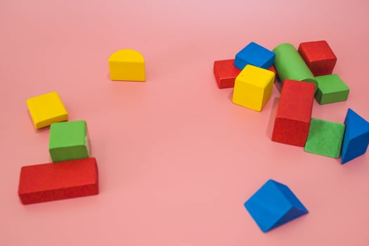 Colorful wooden blocks on pink background. Creativity toys. Children's building blocks. Geometric shapes - cube, triangular prism, cylinder. The concept of logical thinking. photo
