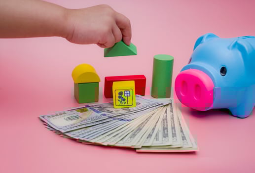 Hand of the kids take a wood block with small  house models on top of block.Concept of saving money for future , investment property and saving money to buy a house. On blur background. photo