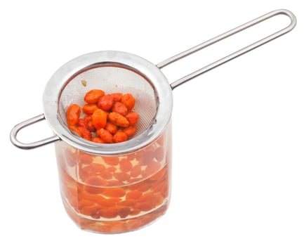 strainer and glass with goji berries infusion photo