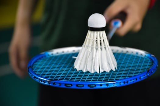 Cream white badminton shuttlecock and racket on floor in indoor badminton court, copy space, soft and selective focus on shuttlecocks. photo