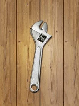 metal adjustable wrenches on a brown wooden background, top view photo