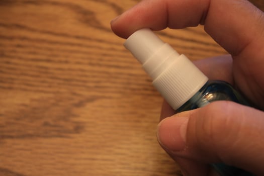 A man's hand holding an alcohol spray bottle on a wooden background. photo