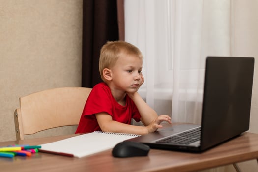 Online distance learning. The child looks carefully at the laptop and studies the drawing lesson online on the Internet. Online school. photo