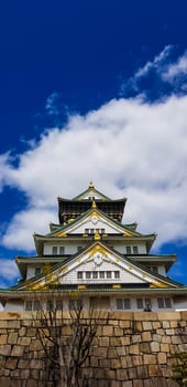 Landscape photo of Osaka Castle in spring, where there are still some cherry blossoms still in bloom.