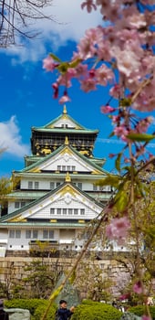 Landscape photo of Osaka Castle in spring, where there are still some cherry blossoms still in bloom.