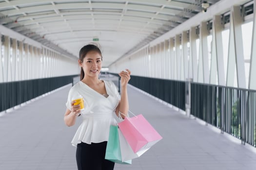Portrait of happy smiling woman with shopping bags in corridor walk way. Beautiful woman with a paper bag. photo