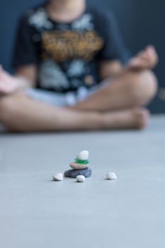 Stack of zen-like pebble stones with child meditating in the background. photo