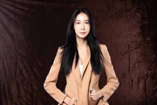 Haft body portrait of beautiful transgender 20s asian woman express feeling smiling confidently on brown background. Business Female smart look blazer has wind blow throw her hair in air, copy space photo