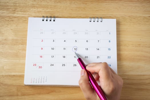 calendar page on table with female hand holding pen, top view photo