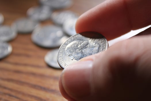 hand picking up a quarter coin in american currency spread on the wooden floor photo