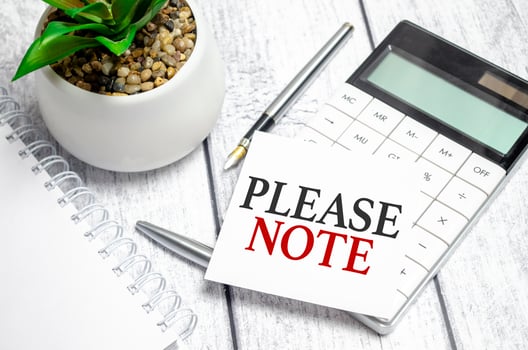 please note words on paper sticker and calculator on wooden background photo