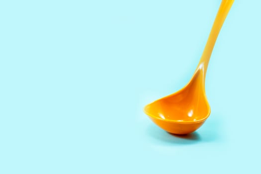 yellow ladle used to scoop soup isolated on a turquoise photo