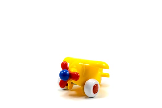Yellow paint plastic toy airplane with red propeller isolated on white photo