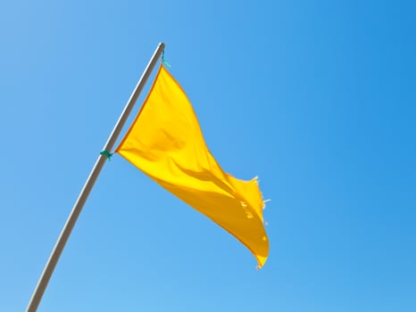 Beach safety warning yellow flag with blue sky photo