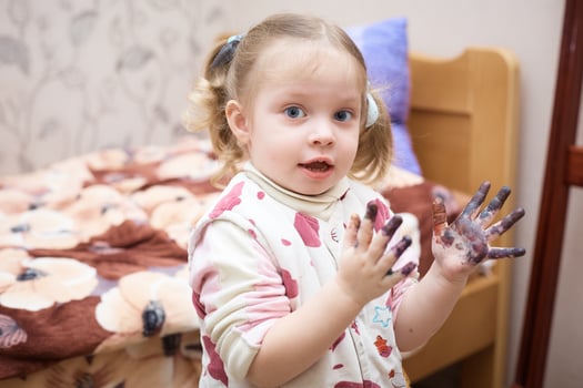 little Caucasian girl with hands in paint after drawing. photo