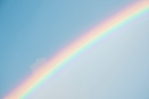 Beautiful view of rainbow amidst clouds covering blue sky on sunny day photo