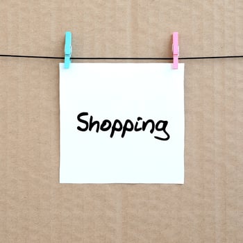 Shopping. Note is written on a white sticker that hangs with a clothespin on a rope on a background of brown cardboard photo