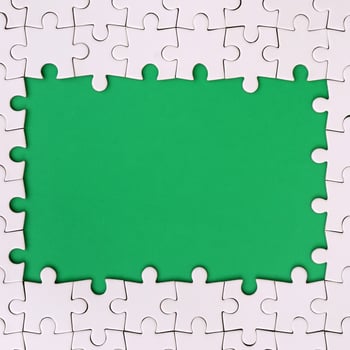 Framing in the form of a rectangle, made of a white jigsaw puzzle around the green space photo