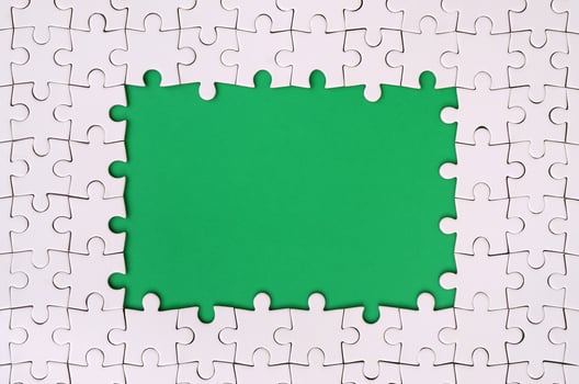 Framing in the form of a rectangle, made of a white jigsaw puzzle around the green space photo
