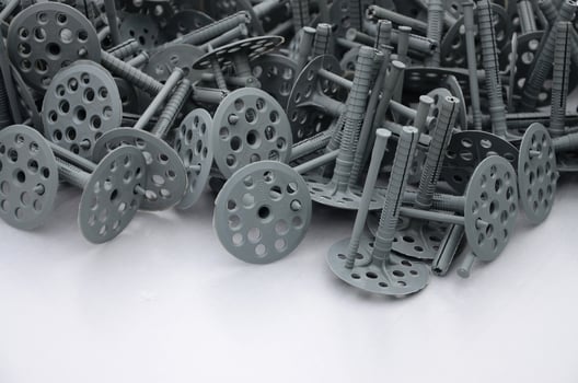 Background of many gray plastic dowels fastening for thermal insulation. A huge pile of plastic bolts with round holey hats lies on a gray foam polystyrene plate photo