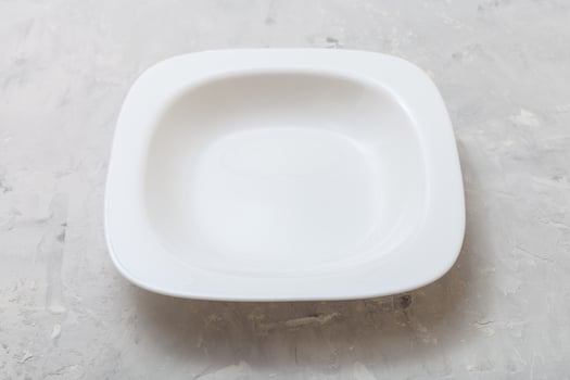 one square white deep plate on gray concrete photo