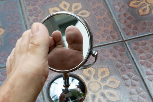 Person looking at the sole of the foot in a mirror. photo