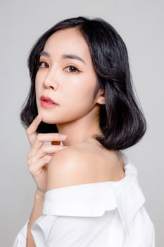 Asian woman short hair with Perfect clean fresh skin. Cute female model with natural makeup and sparkling eyes on grey isolated background. Facial treatment, Cosmetology, beauty Concept. photo