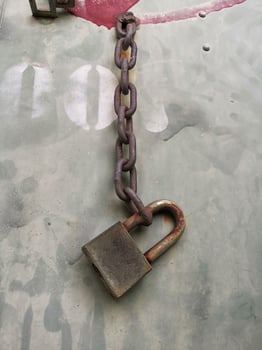 An old rusty padlock closed on a massive chain on iron background photo