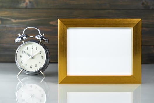 Picture mock up with golden frame and alarm clock photo