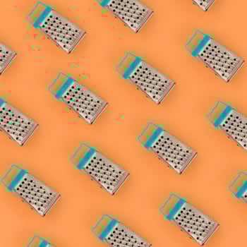 Small stainless steel graters lies on a pastel colored paper. Kitchen accessories. Tools for cooking. Flat lay top view photo