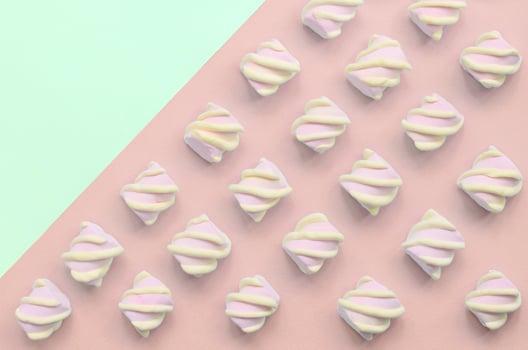 Colorful marshmallow laid out on turquoise and pink paper background photo