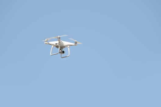 Big white drone hovering in a bright cloudless blue sky photo