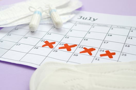 Menstrual pads and tampons on menstruation period calendar with red cross marks lies on lilac background photo