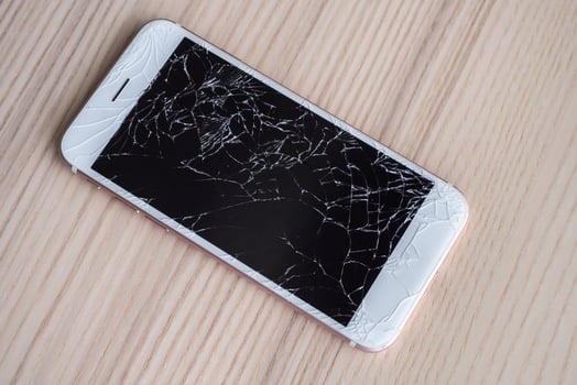 broken glass of mobile phone screen on wooden background photo