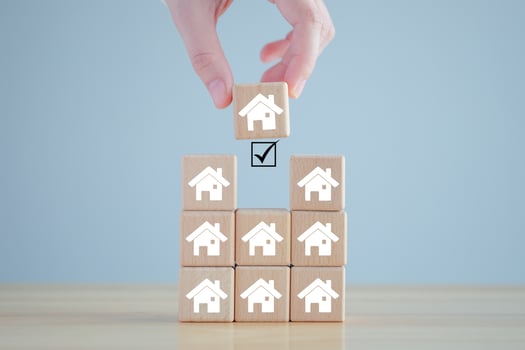 Real estate, Property investment and asset management concept. Hand holding house icon on wood block from many house. Decision to choose the best property with your right. Choosing suitable housing. photo