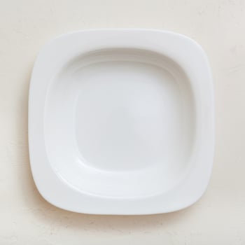 top view of square white deep plate on plaster photo