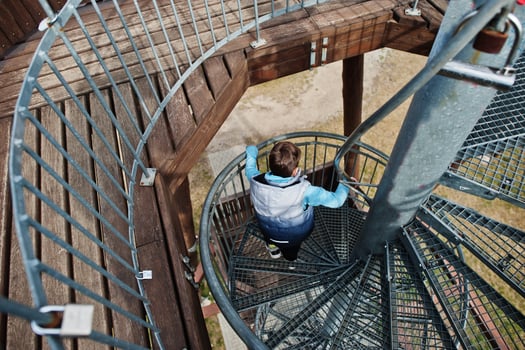 Boy walk at spiral staircase on wooden observation tower. photo