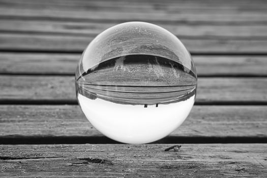 Glass ball on a wooden pier at a Swedish lake at dusk in black and white. Nature photo