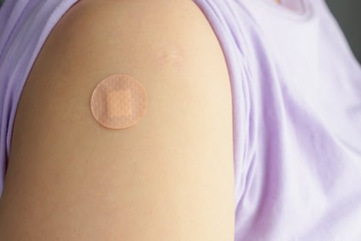 Close up circle brown adhesive bandage on patient arm after medicine injection or vaccination photo