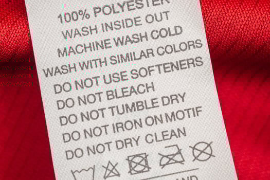 White laundry care washing instructions clothes label on red jersey polyester sport shirt photo